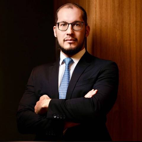 Guilherme Sivieri Reyna, de terno escuro e braços cruzados